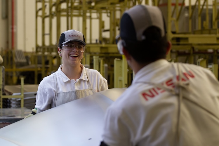Funcionária sorri para um funcionário de costas no prédio da Estamparia do Complexo Industrial da Nissan em Resende